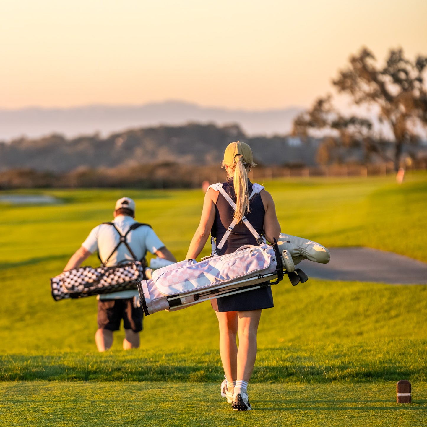 Two golfers walking on a golf course with El Camino golf bag in Pink/White Checker