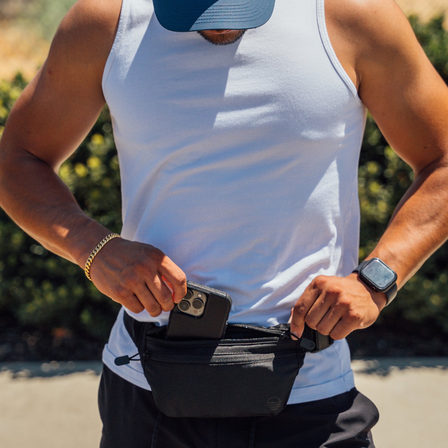 Black Runner Sling worn by a man as he places his phone inside