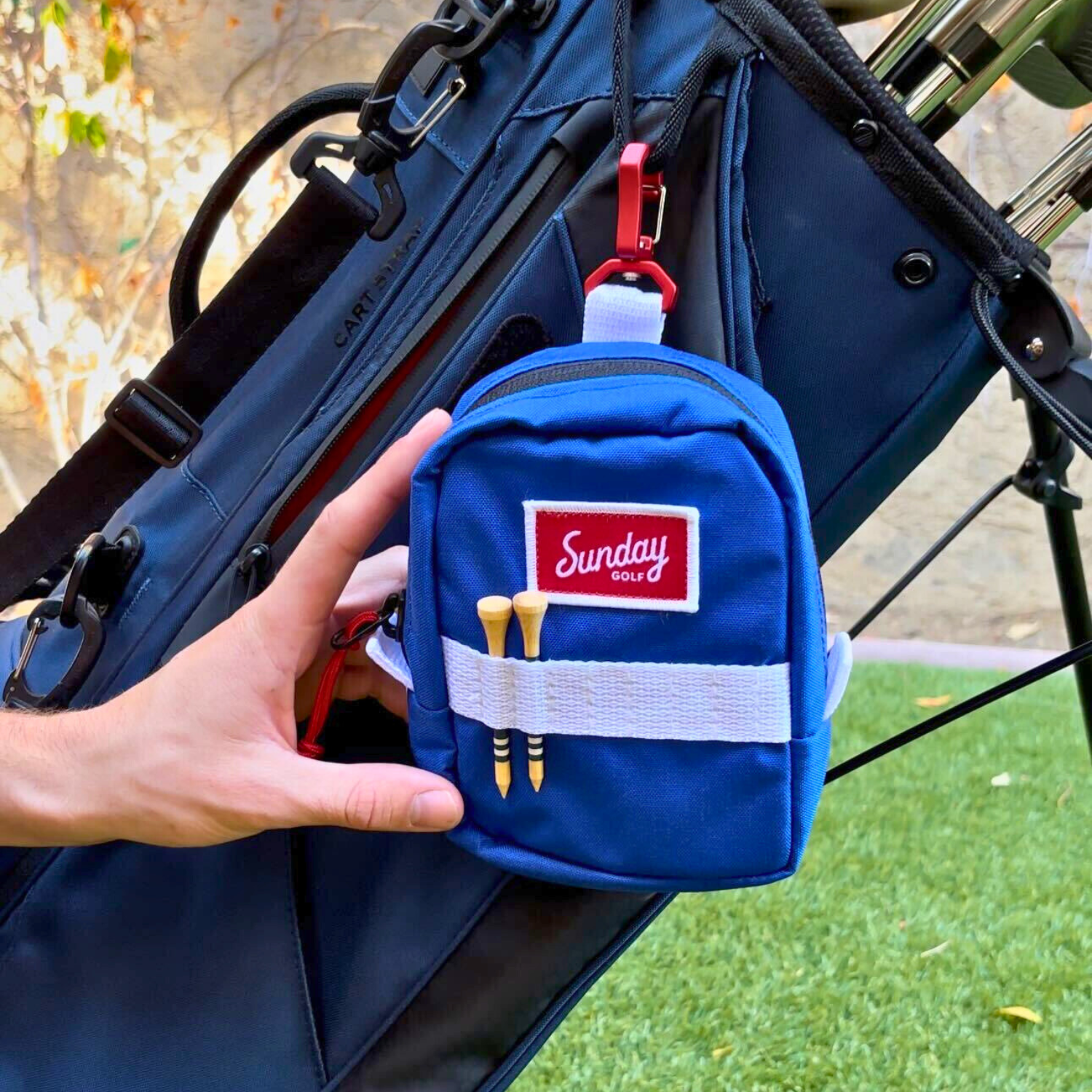 Blue red white range finder pouch hooked on a golf bag with bamboo golf tees at its front