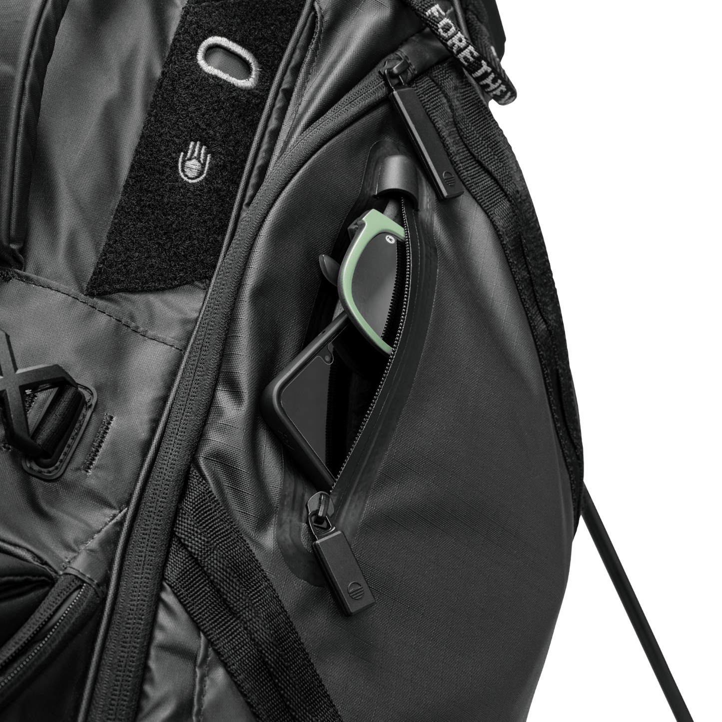 A close up shot of black Ranger golf bag's valuables pouch with a phone and sunglasses inside