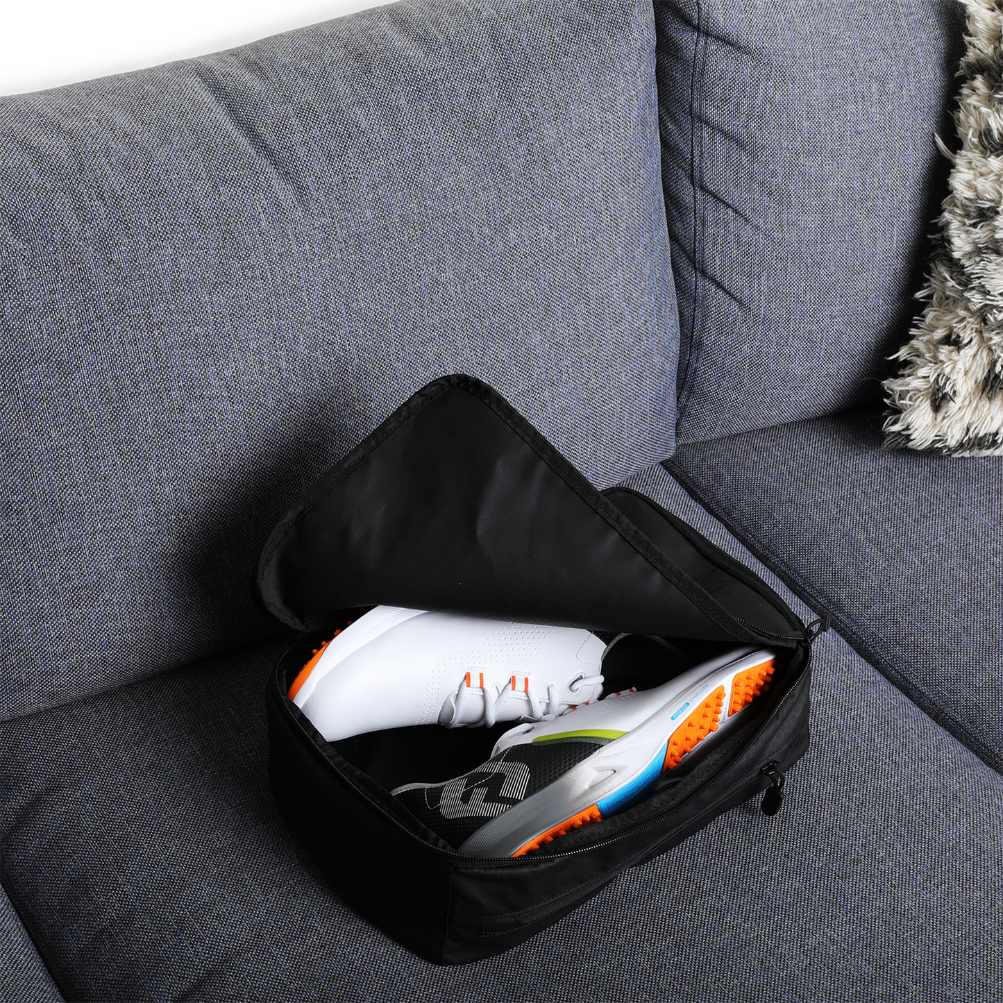 A pair of rubber shoes inside a golf shoe travel bag on a couch