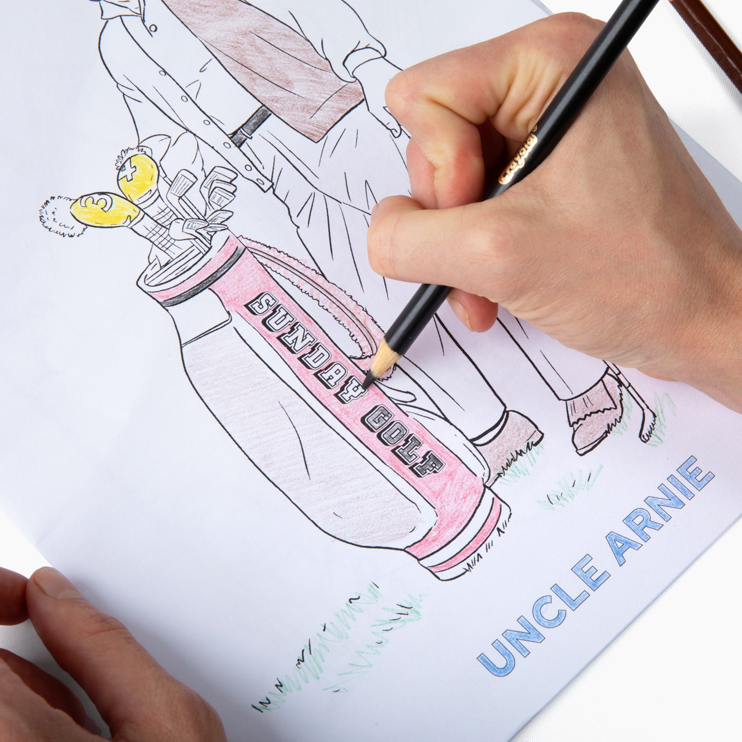 Coloring an illustration inside the book on golf bags using a color pencil