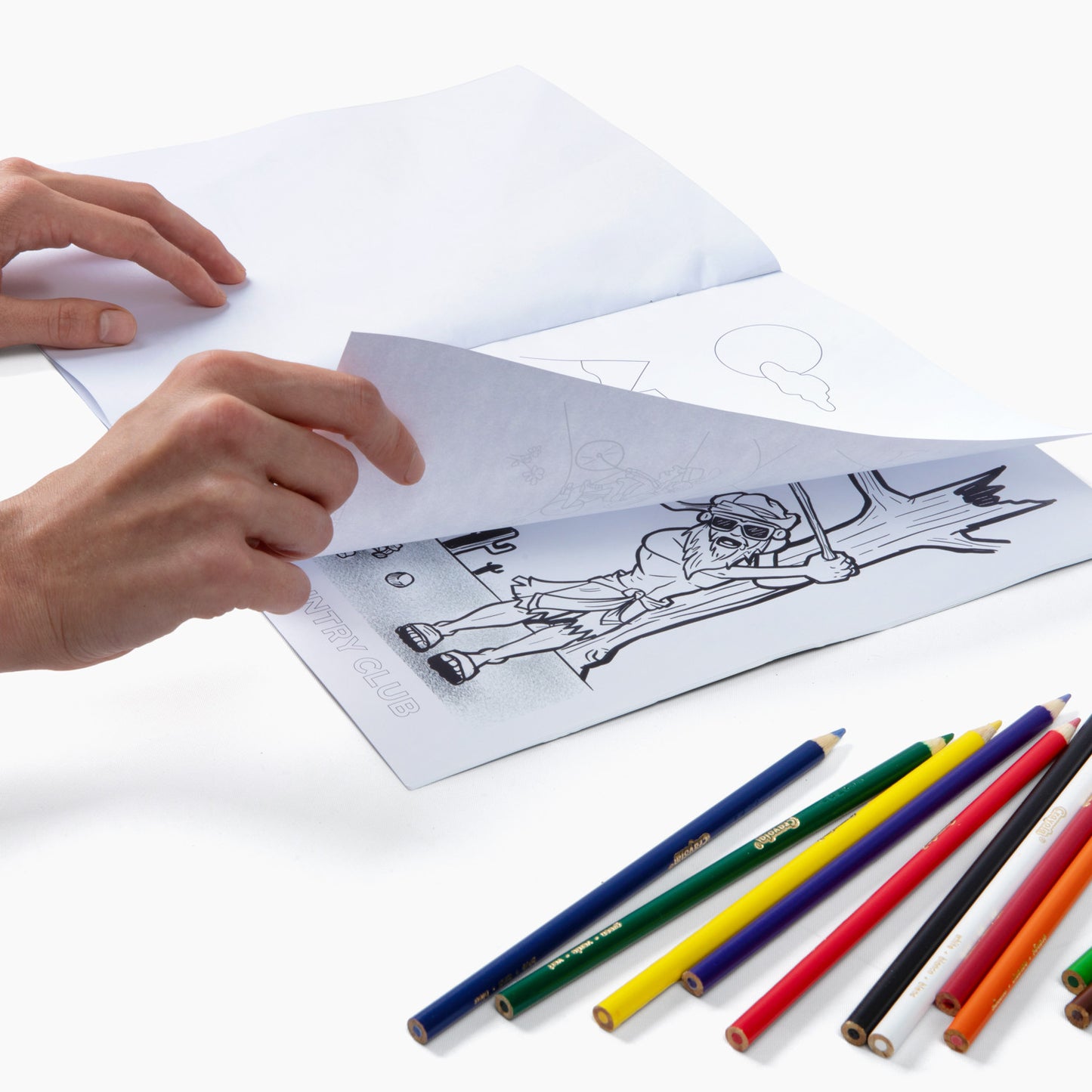 Flipping the pages of the book on golf bags with color pencils beside it
