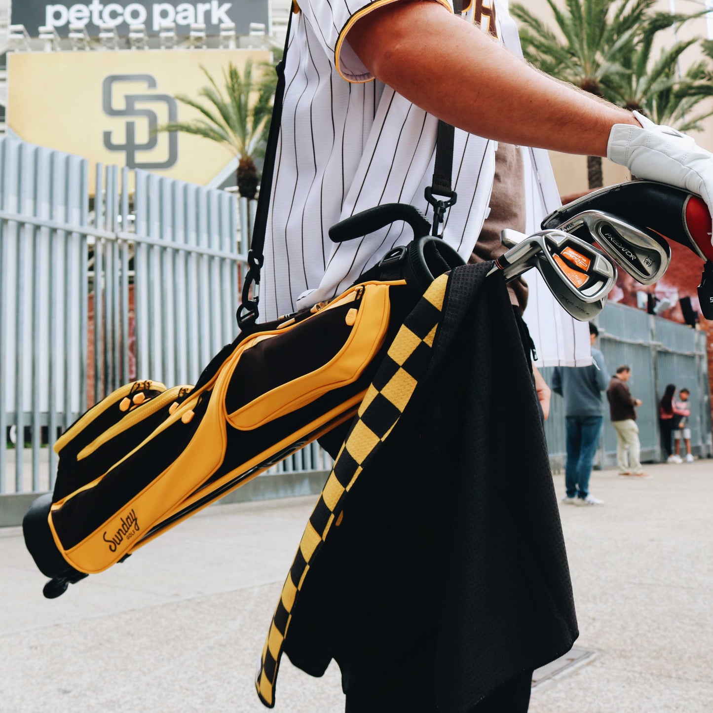 A close up of Loma golf bag in friars brown being carried with golf clubs and golf towel in it