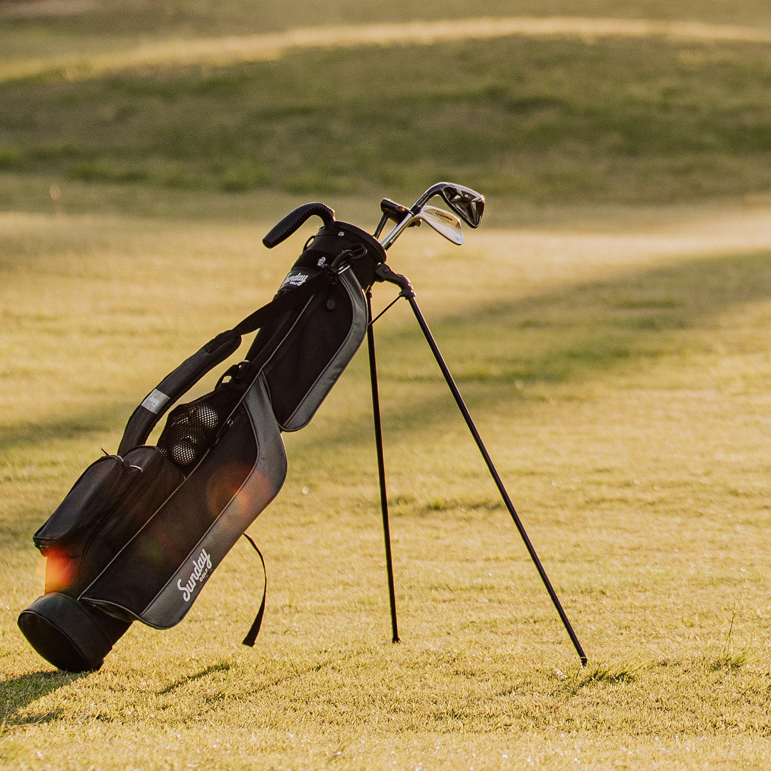 A full front shot of standing Loma golf bag in matte black with single strap on golf course