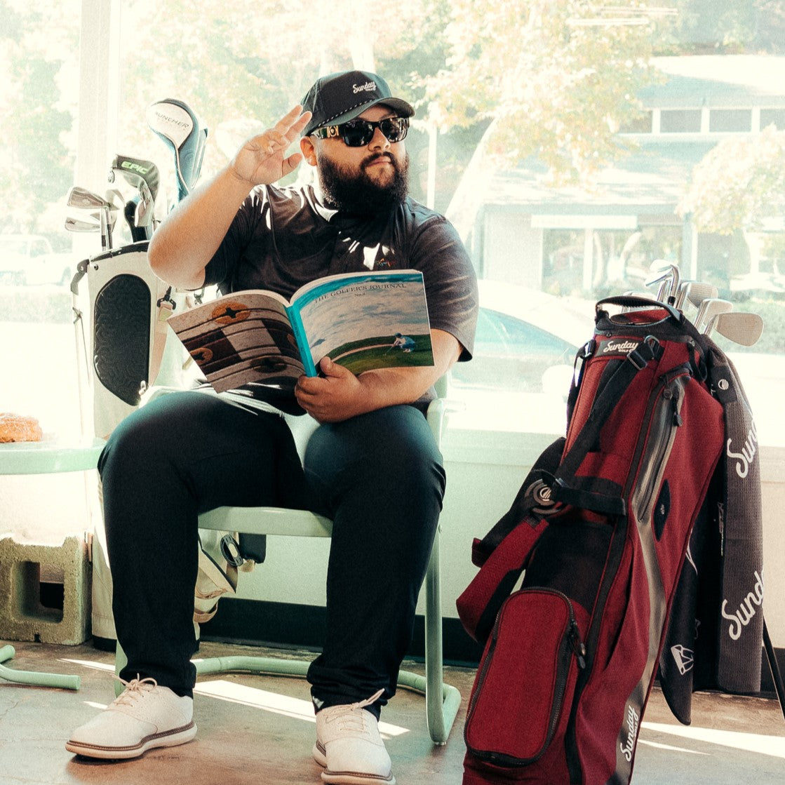 A man wearing black Porter Lite golf hat while sitting beside his golf bag