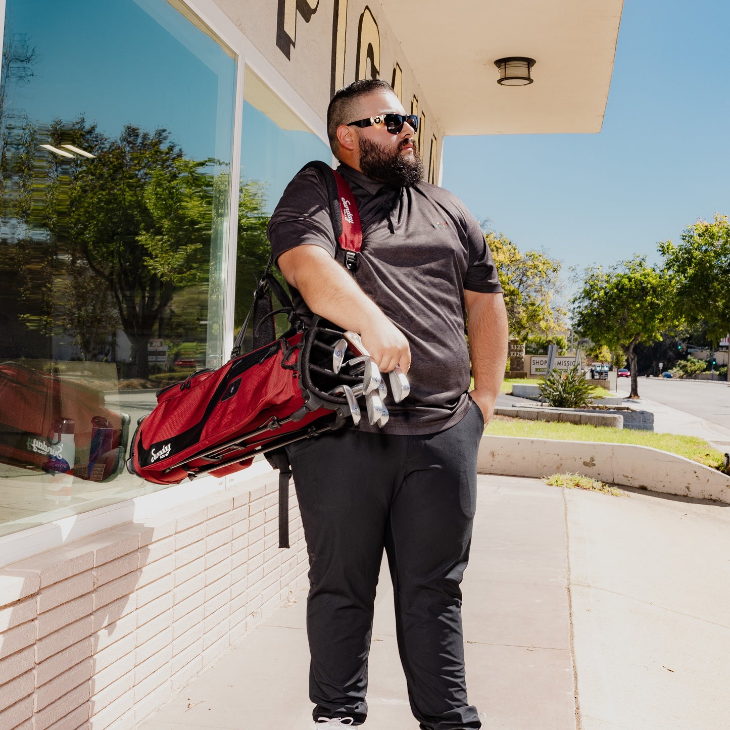 A man carrying El Camino golf bag in deep red burgundy