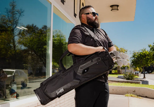 man carrying sunday golf bag the loma in black vegan leather