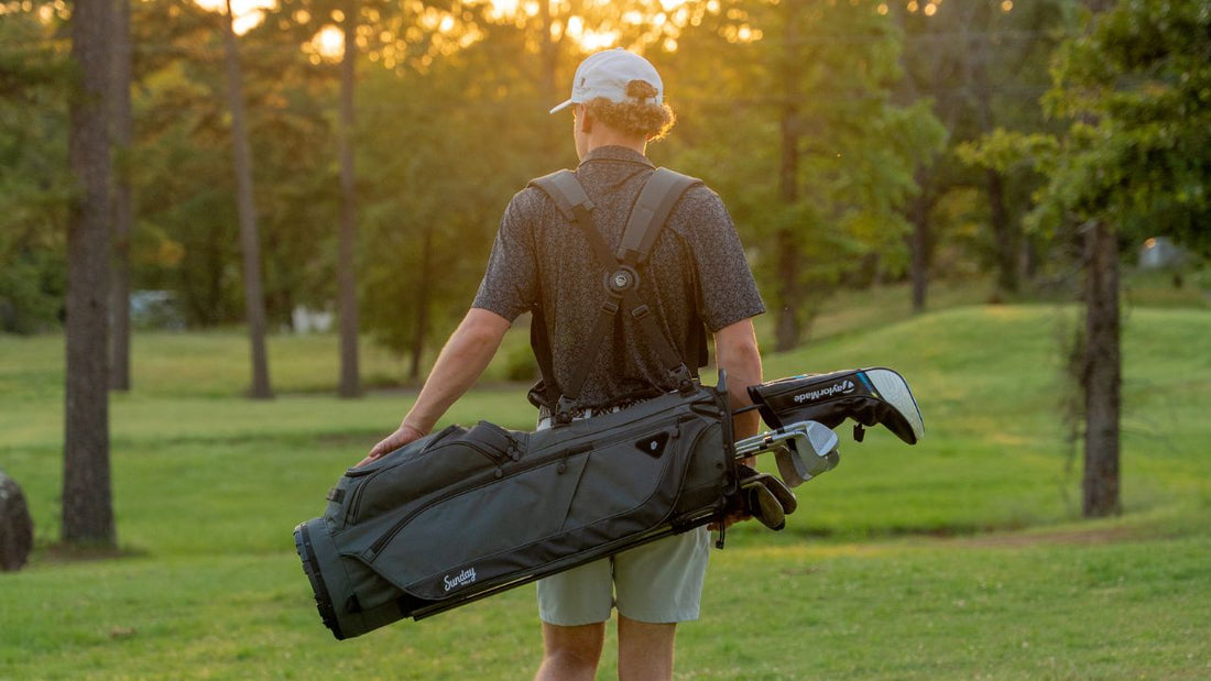 A man in black carrying his Sunday golf Loma bag in Midnight Green Par 3 bag