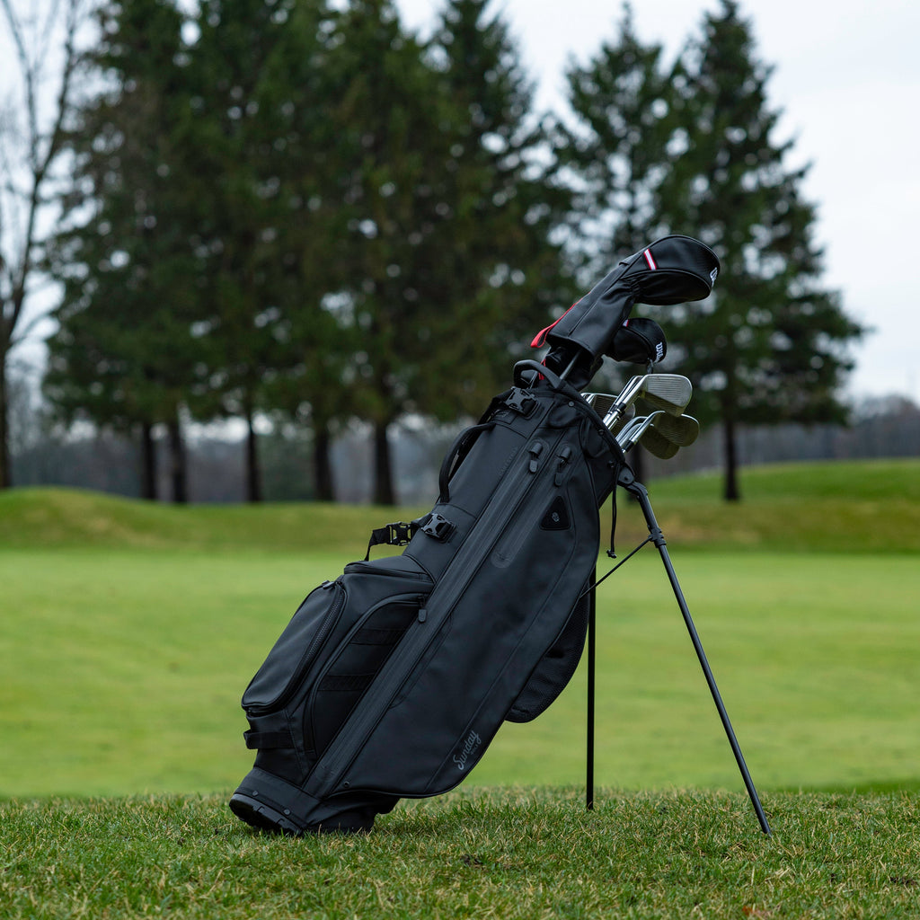 Golf bag with clubs on a grassy field with trees in the background