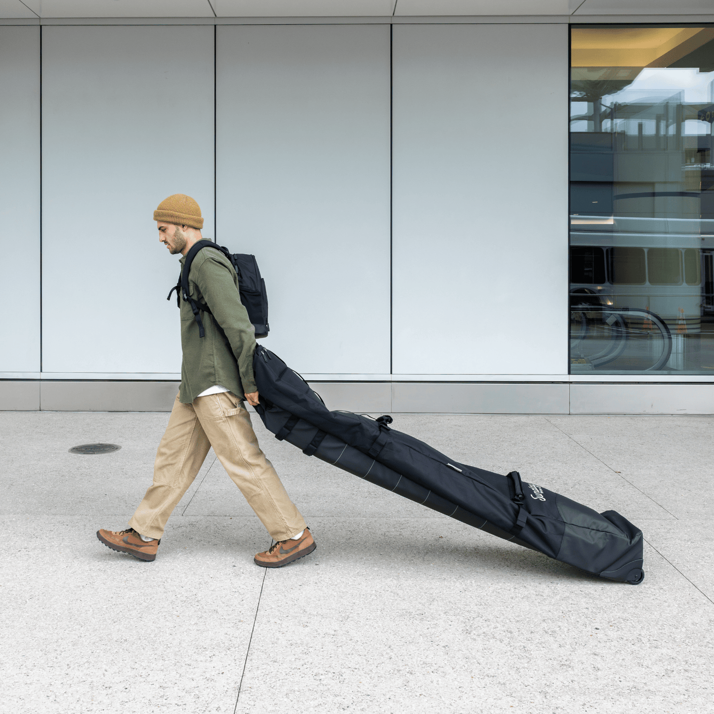 Man walking with the Drifter Snow Travel Bag in an airport setting.