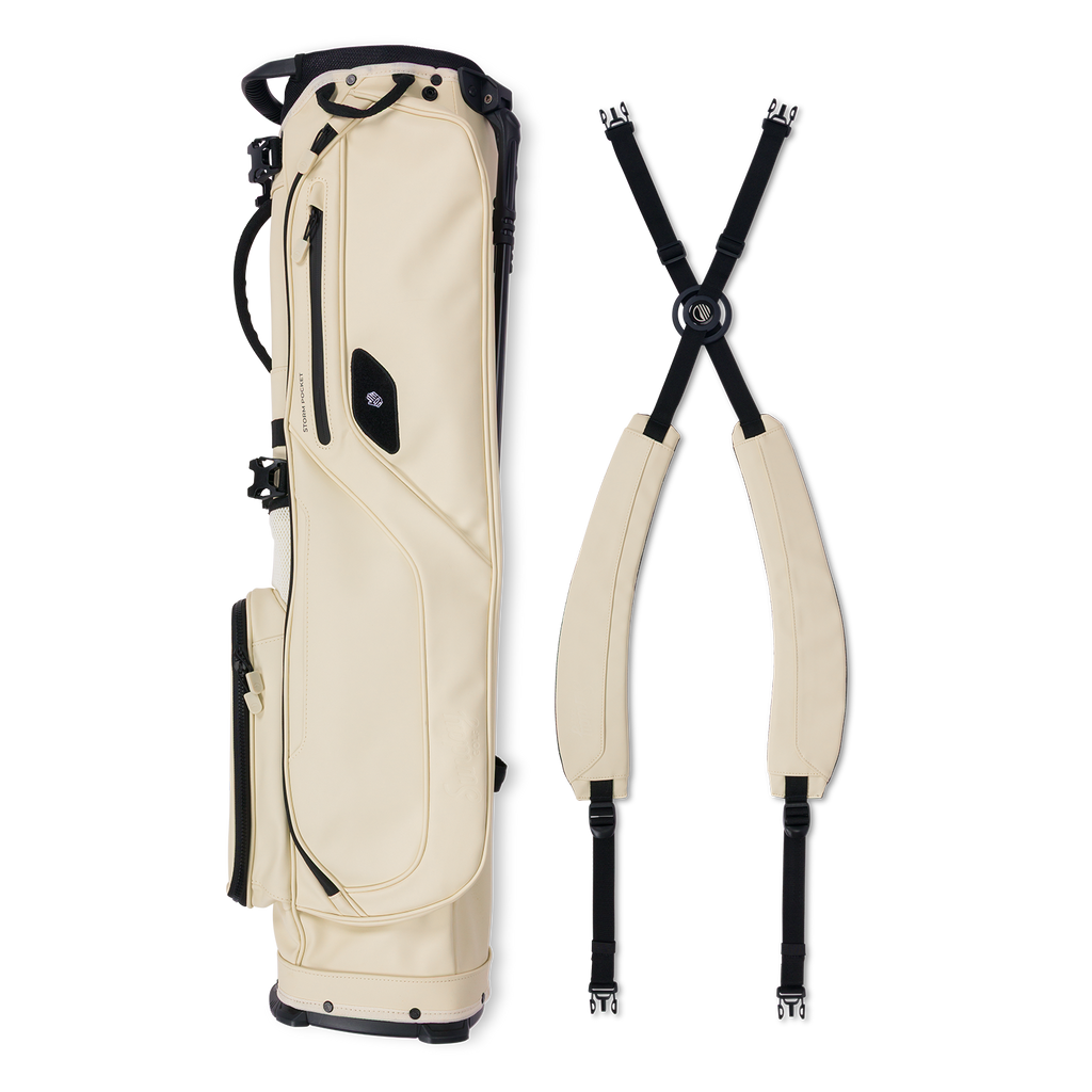 A full shot of El Camino S-class golf bag in Cream laying flat sideways beside its double strap 
