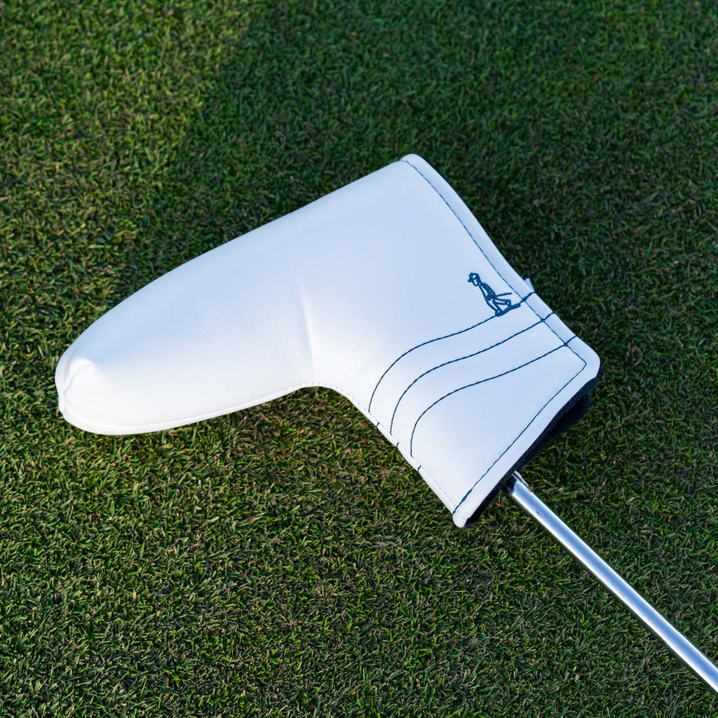 Front shot of blade putter golf headcover in white/navy vegan leather in a green grass setting
