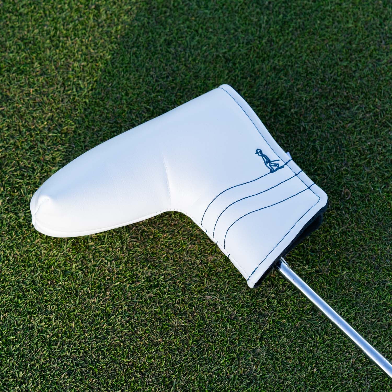 Front shot of blade putter golf headcover in white/navy vegan leather in a green grass setting

