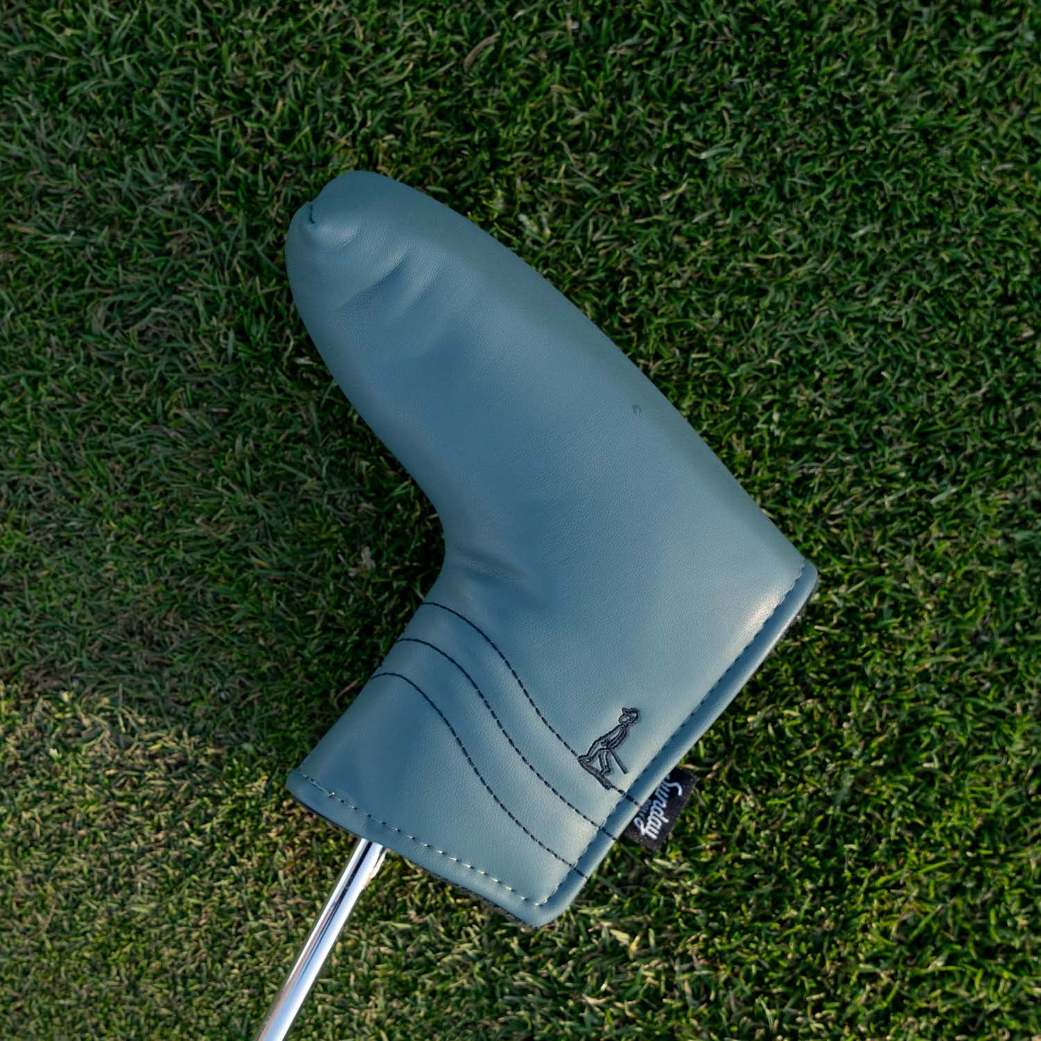 Front shot of blade putter golf headcover in midnight green vegan leather in a green grass setting