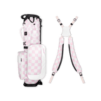 A full shot of a checkered Pink & White Recess kids golf bag laying flat sideways beside its double straps
