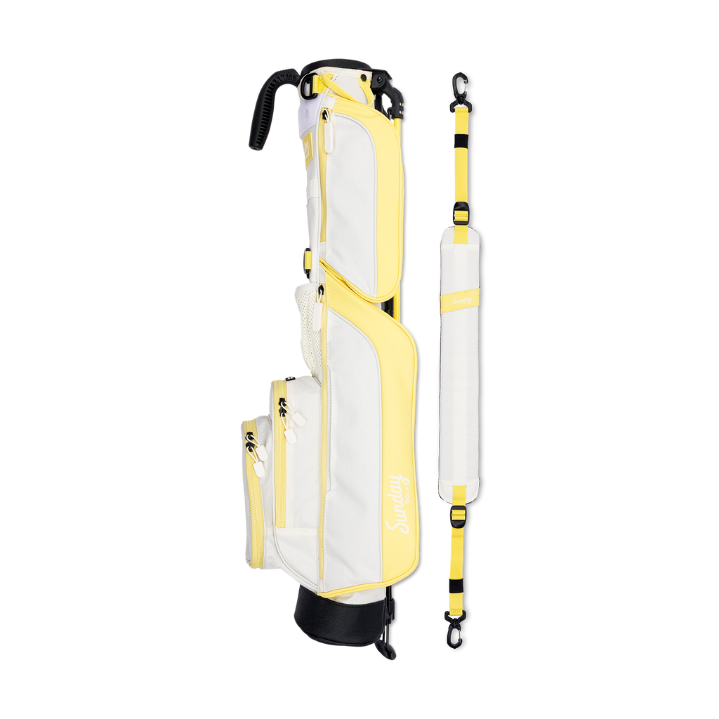 A full shot of Loma golf bag in Mindy Lemon laying flat sideways beside its single strap