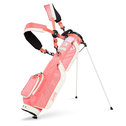 A full front shot of standing Loma XL golf bag in coral with double strap