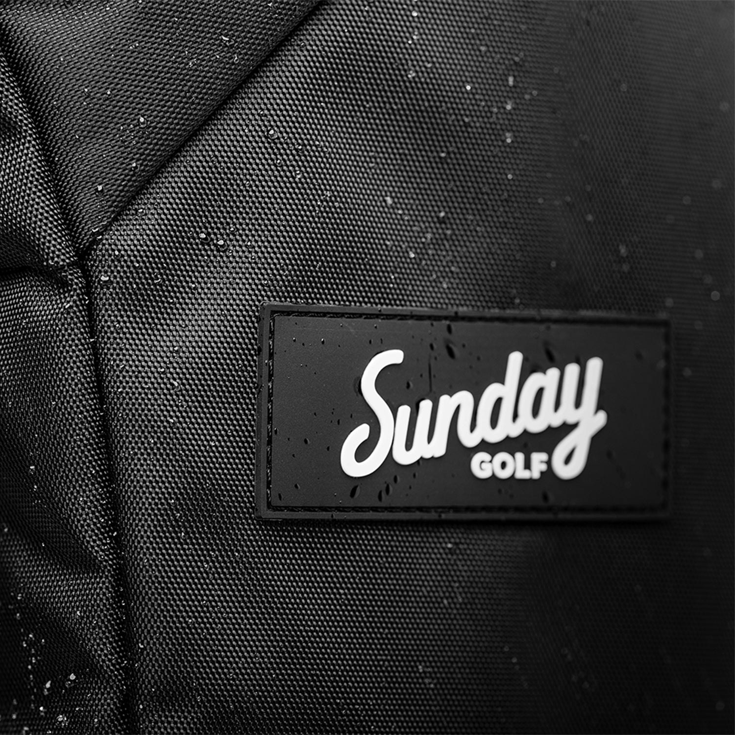 A close up shot of matte black rain hood's water repellent material and logo