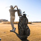 A man playing on the course while his Big Ri golf bag in mossy oak country dna is standing behind him