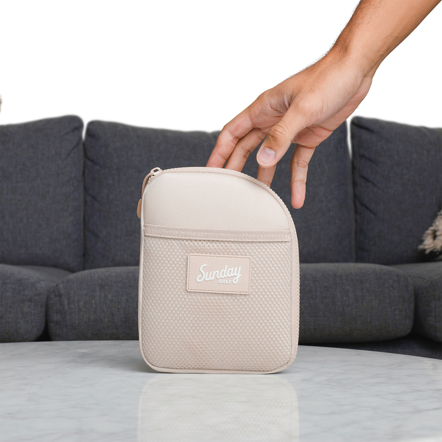 A hand about to grab a toasted almond nickel bag valuables pouch from a table