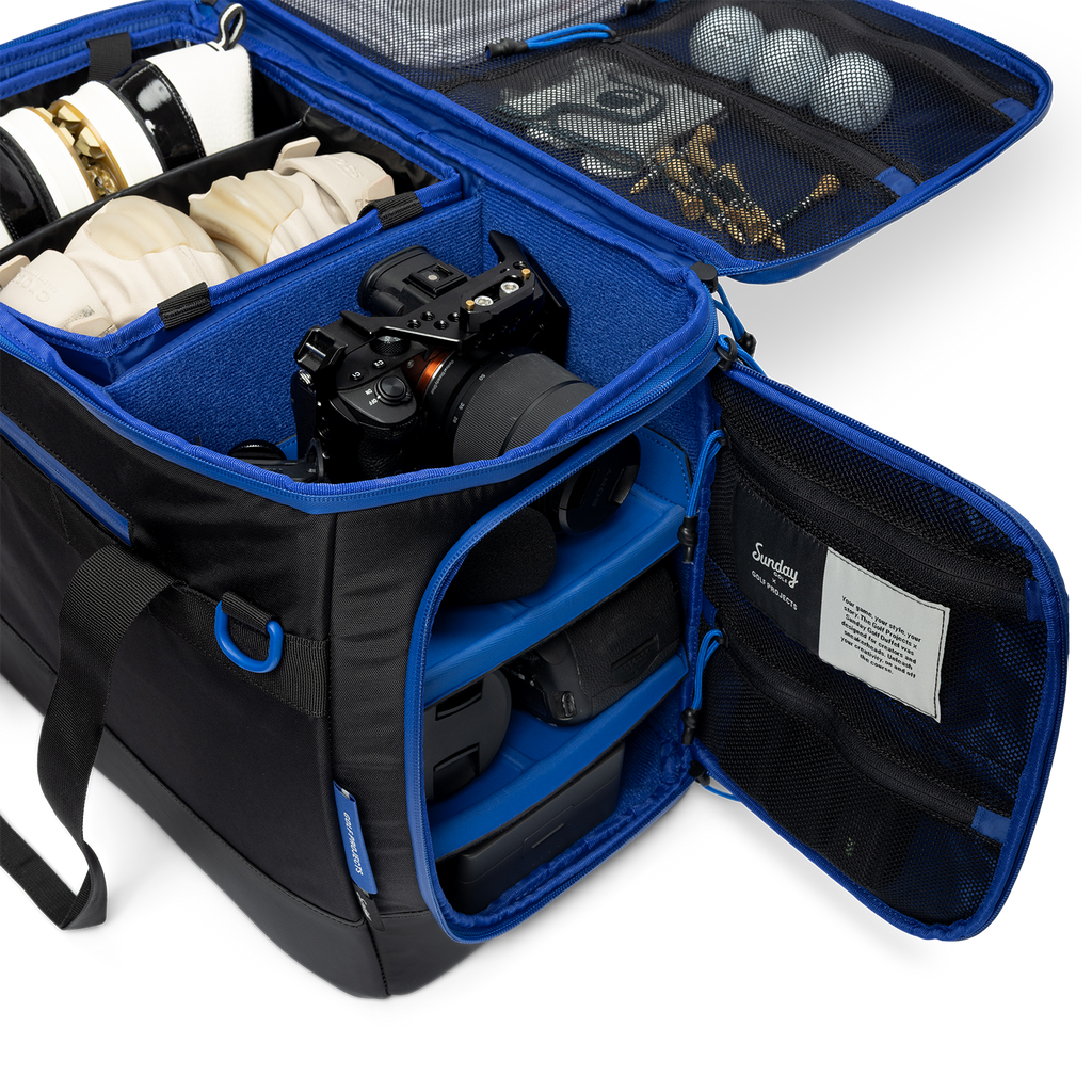 Sunday Golf's Creator Duffle Bag showcasing compartments containing camera equipment, accessories, and golf balls.