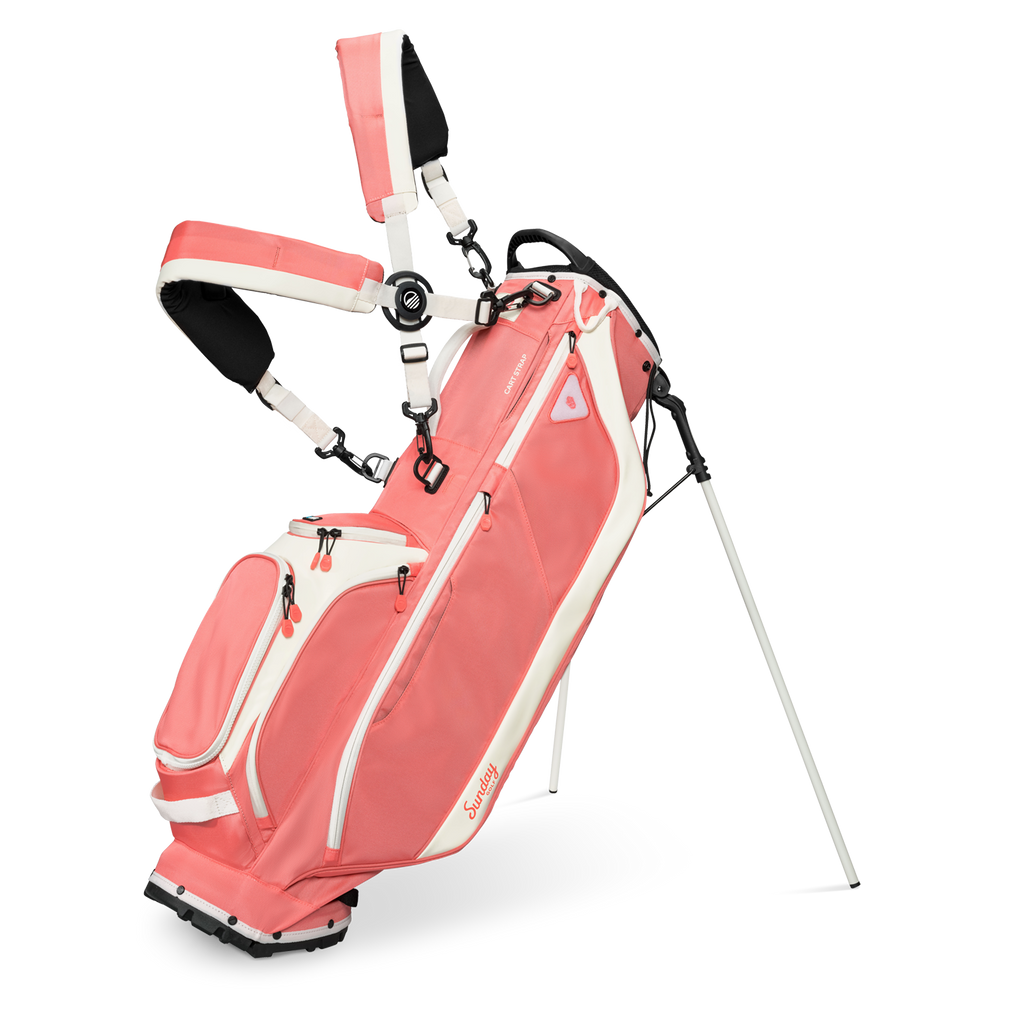 A full front shot of standing Ryder golf bag in coral with double strap