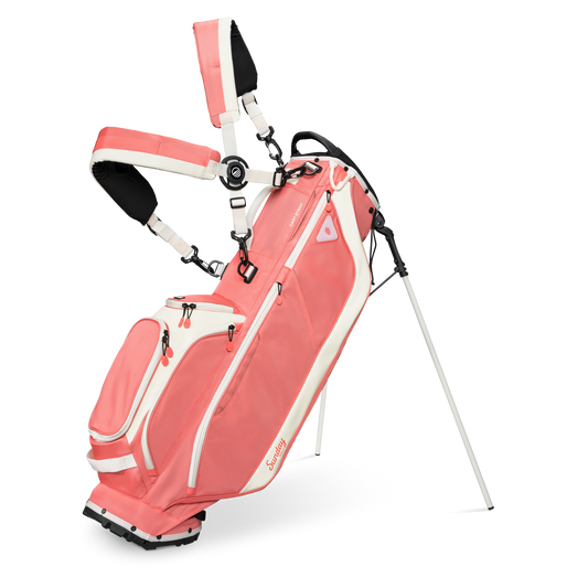 A full front shot of standing Ryder golf bag in coral with double strap