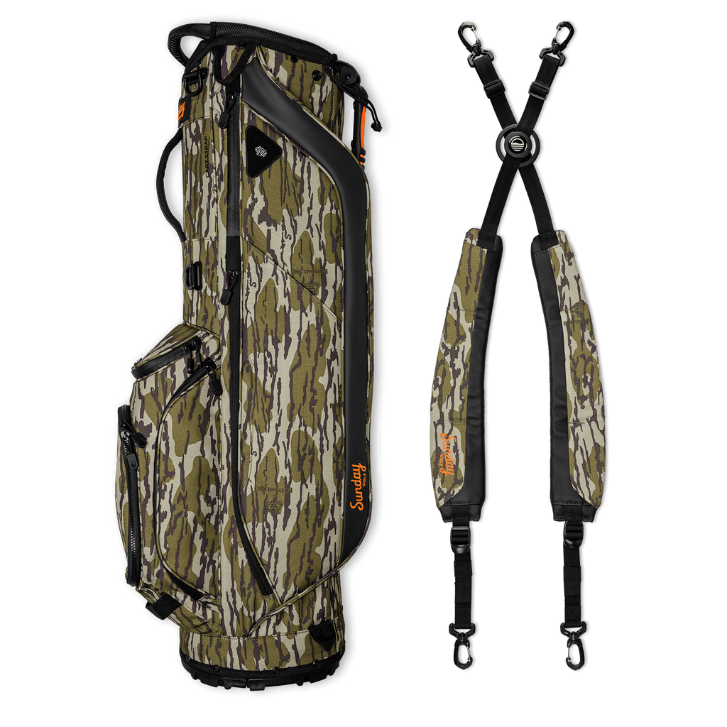 A full shot of Ryder golf bag in mossy oak bottomland laying flat sideways beside its double strap