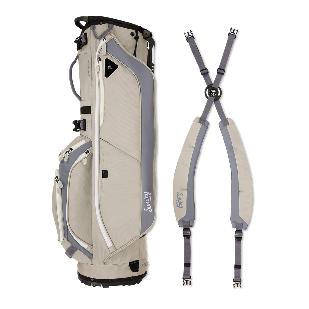 A full shot of Ryder golf bag in Cool Gray laying flat sideways beside its double strap
