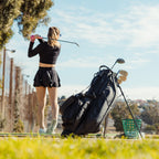 A woman playing on the course while her Ryder S-Class golf bag in black vegan leather is standing behind her