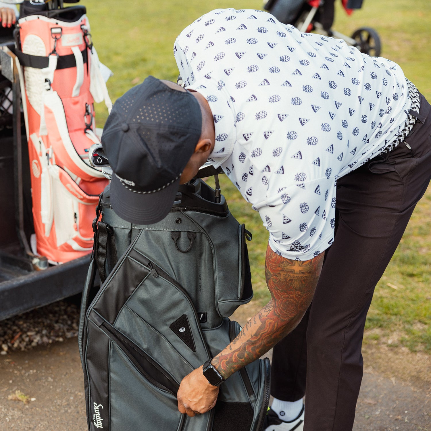 A man unzipping the side pocket of Big Rig golf bag in midnight green
