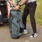 A man holding a Big Rig golf bag in midnight green showing its side pockets