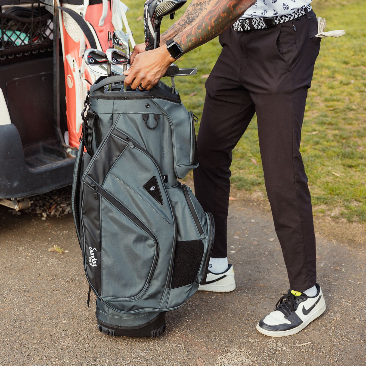 A man holding a Big Rig golf bag in midnight green showing its side pockets