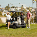 A man and a woman standing beside a golf cart with Big Rig golf bags in matte black and toasted almond colors at its back