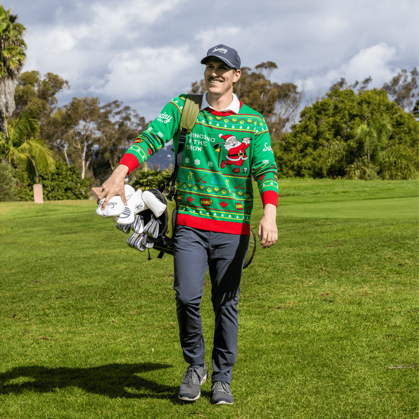 Man wearing the Ugly Sweater carrying golf clubs on a golf course