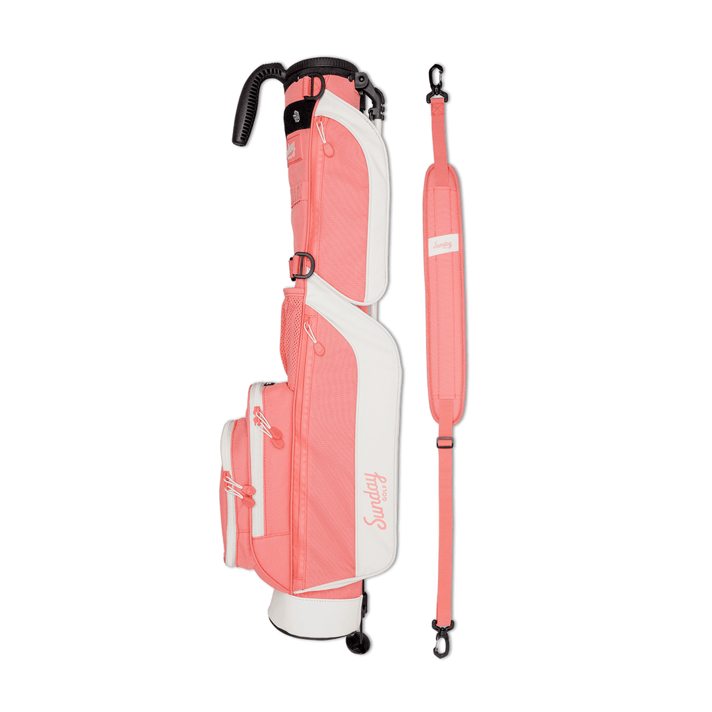 A full shot of Loma golf bag in coral laying flat sideways beside its single strap