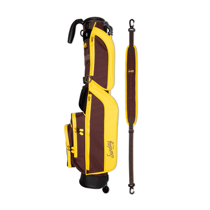 A full shot of Loma golf bag in friars brown laying flat sideways beside its single strap