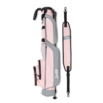 A full shot of Loma golf bag in flamingo pink laying flat sideways beside its single strap