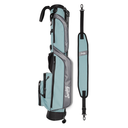 A full shot of Loma golf bag in seafoam laying flat sideways beside its single strap
