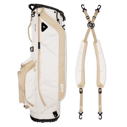 A full shot of Ryder golf bag in toasted almond laying flat sideways beside its double strap