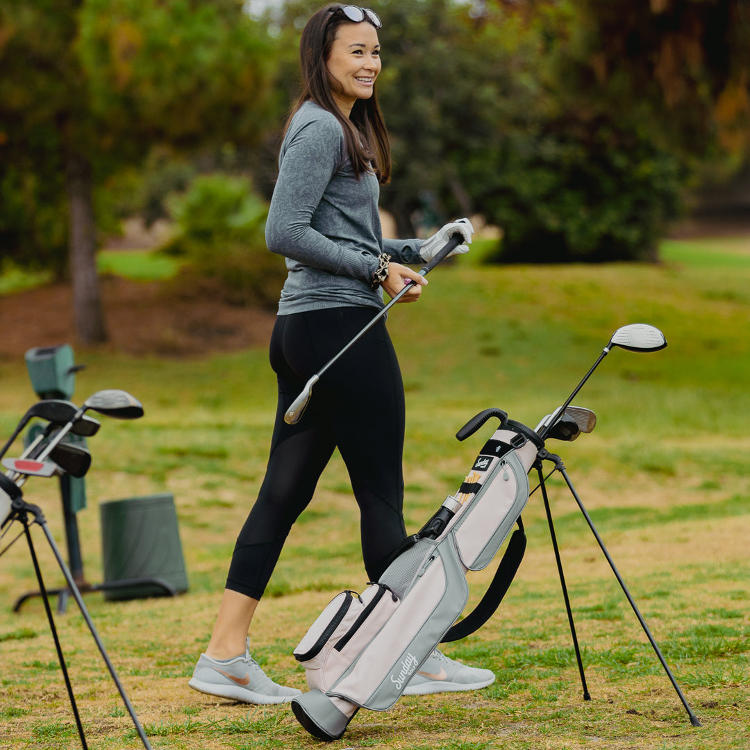 A golfer with a flamingo pink Loma golf bag beside her