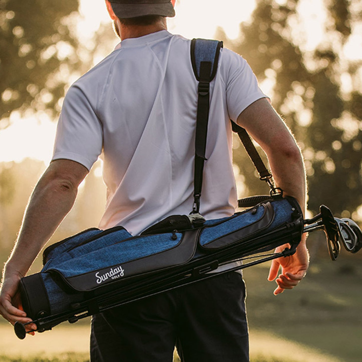 A man carrying a cobalt blue Loma golf bag using its single strap