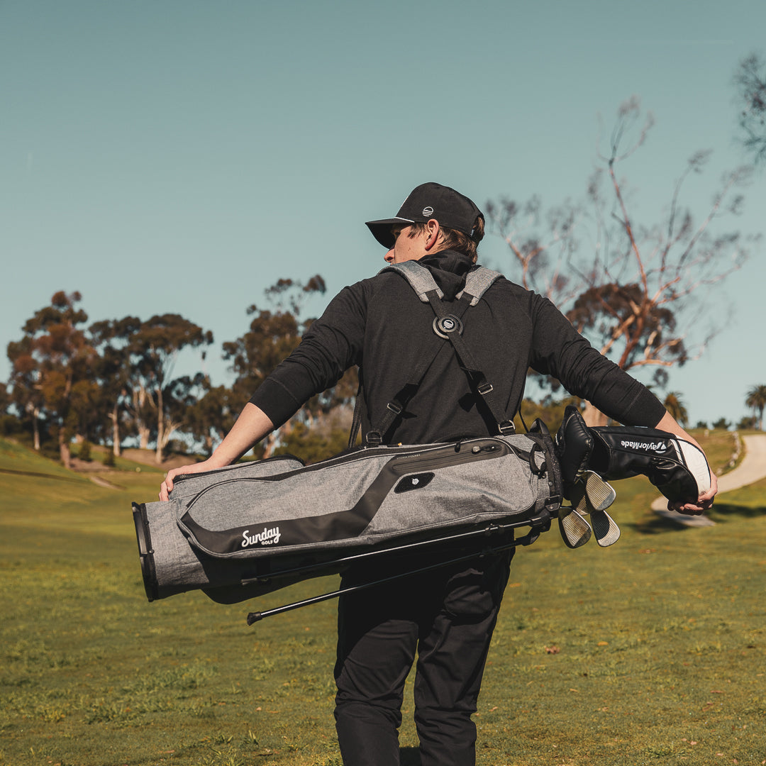 A guy walking on the course while carrying an El Camino golf bag in heather gray