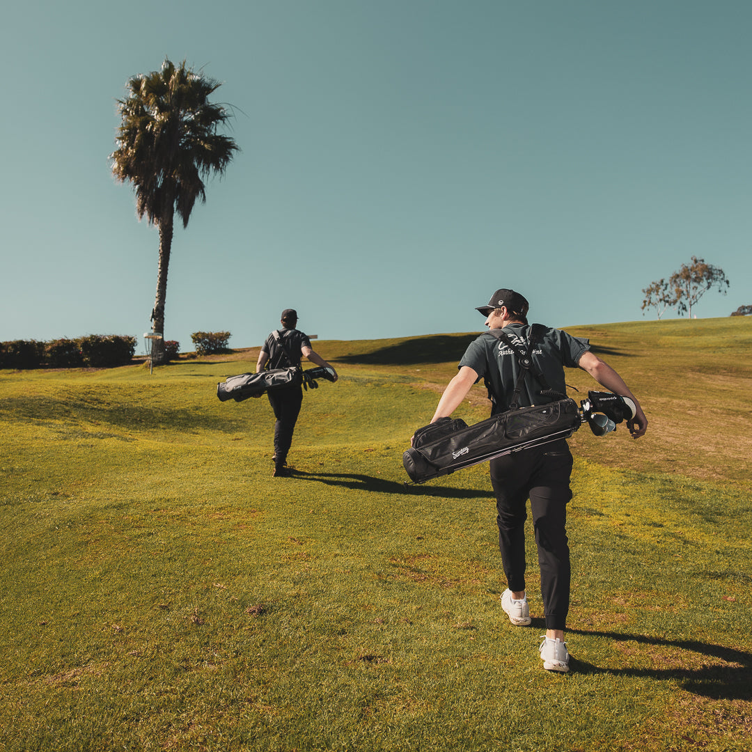 Two men carrying Loma XL golf bags while walking on the golf course