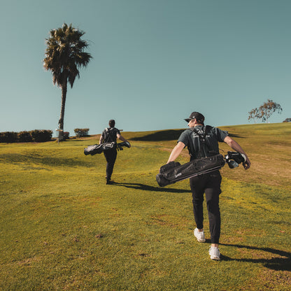 Two men carrying Loma XL golf bags while walking on the golf course