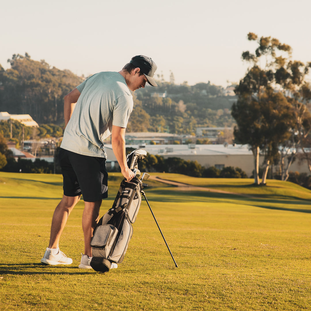 A man holding Loma XL golf bag in heather gray on the course 
