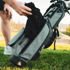 A jacket being pulled out of the storage pouch on the Loma XL golf bag in heather gray