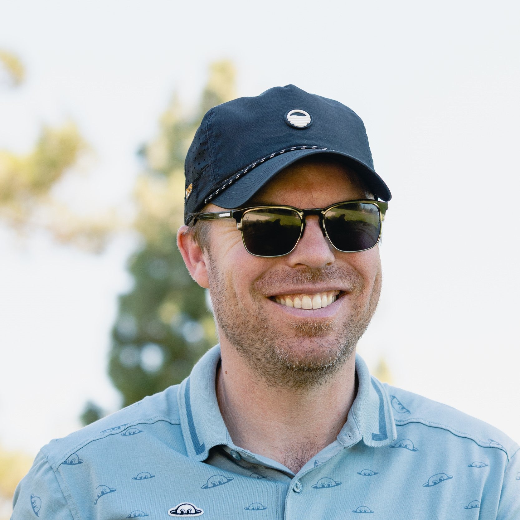 A man smiling wearing black Porter Lite golf hat