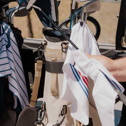 Golf clubs being cleaned one by one from a Ryder golf bag in toasted almond